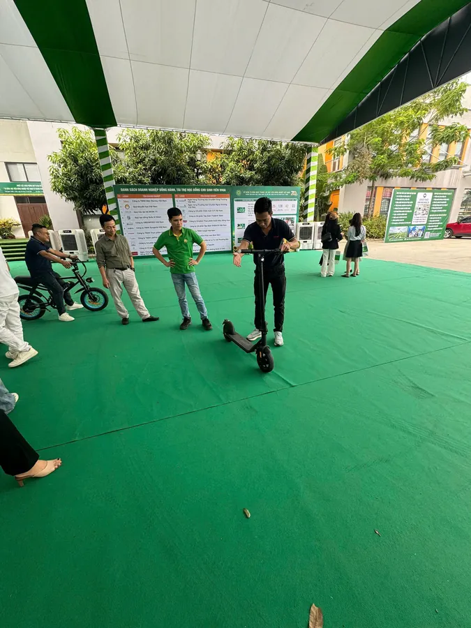 Khu chạy thử trong khuôn viên Học viện: khách lái xe đạp điện và xe scooter điện trên thảm xanh.